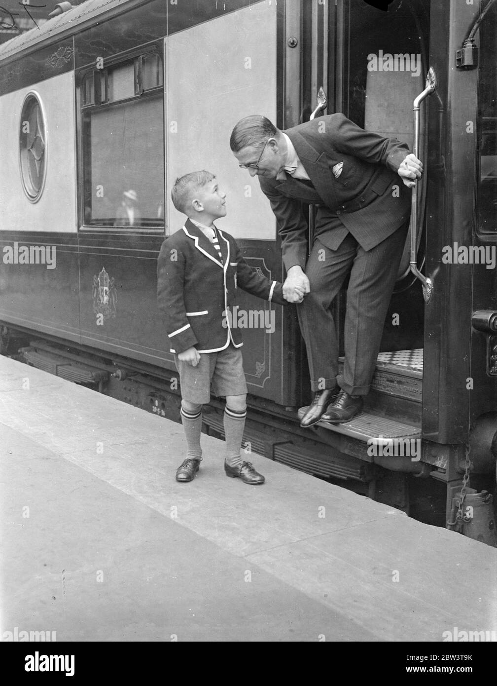 Henry Hall . 'RMS Queen Mary' Gastdirigent verlässt Waterloo auf dem Bootszug. Henry Hall , Leiter der BBC Dance Band, der Gastdirigent an Bord der "RMS Queen Mary" auf ihrer Jungfernfahrt sein soll, verließ Waterloo Station auf dem Bootstrian, um den Linienschiff in Southampton zu besteigen. Auf der Reise, Hall ist es, Konzerte nach England und Amerika zu übertragen. Foto zeigt, Henry Hall Bieten Abschied von seinem Sohn Michael in Waterloo. 27 Mai 1936 Stockfoto