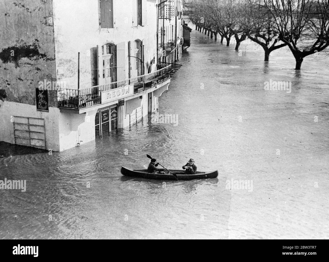 Streetsbecome Flüsse in Westfrankreich . Bäume in Westfrankreich sind fast bis zu den Zweigen durch das Hochwasser untergetaucht , die keine Anzeichen von Abklingen geben . Die Türen vieler Gebäude sind unter Wasser, und Boote sind die einzigen Transportmittel. Foto zeigt, Reisen durch die überflutete Stadt Le Beole in der Gironde, Westfrankreich. Beachten Sie die Bäume in Backgaund mit ihren Stämmen fast vollständig untergetaucht. Januar 1936 Stockfoto