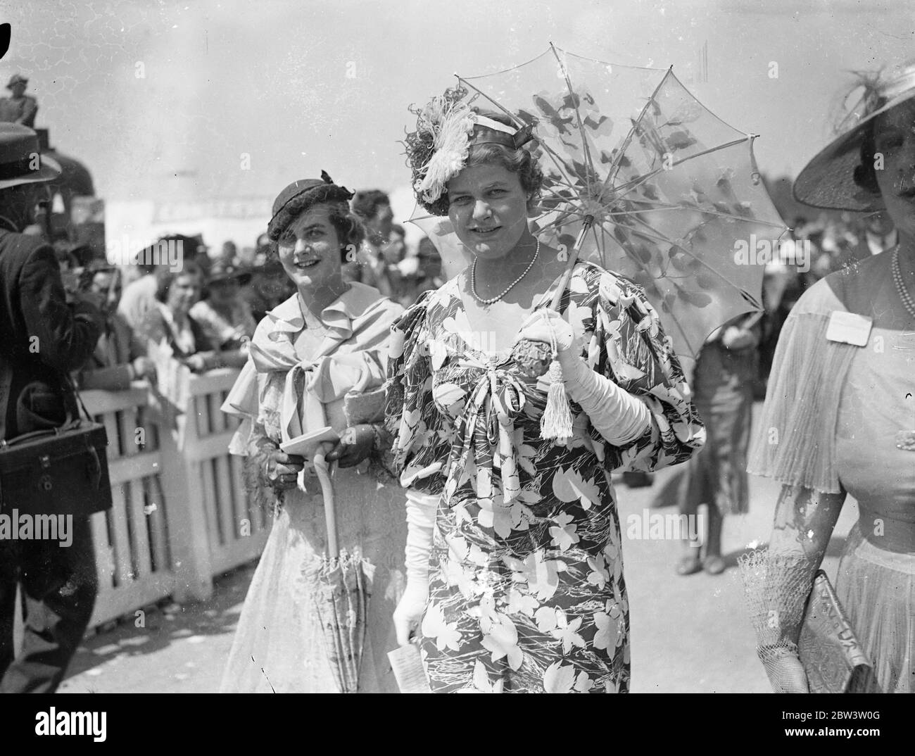 Weißer Sonnenschirm Und Ungewöhnliche Hut Mode Bei Ascot. Ascot, auf Royal Hunt Cup Tag, mit noch besseren Wetterbedingungen als auf der Eröffnung bevorzugt, sah eine noch größere Vielfalt an schönen Mode. Foto zeigt: EIN auffallend ungewöhnlicher Hut mit weißer Sonnenschirm Mode bei Ascot. 17 Juni 1936 Stockfoto