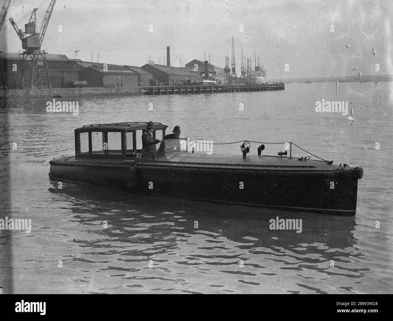 Polizeiwache 'Queen Mary' von den Sehenswürdigkeiten in Southampton. Tausende von Ostern Besucher . Die Polizei von Southampton hatte einen wässrigen Schlag, als Tausende von Osterurlaubern ankamen, um die "Queen Mary" zu inspizieren. Zwei uniformierte Polizisten waren in einem Schnellboot im Einsatz, um unerlaubte Vergnügungsboote daran zu hindern, in das Ocean Dock einzusteigen, wo der riesige Linienschiff liegt. Foto zeigt, uniformierte Polizei Bewachung der Ocean Dock in einem Schnellboot als Vergnügen Dampfer Pässe. 13. April 1936 Stockfoto