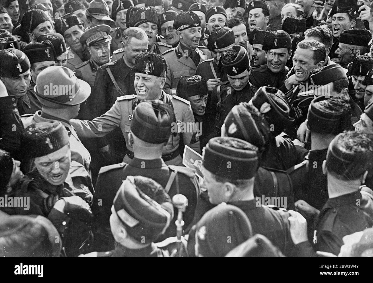 Mussolini, Hagel Kerl gut getroffen! . Signor Mussolini übergibt Weste an eine herzhafte Guffaw, als er einen Offizier auf die Schulter bei einer Kundgebung von viertausend piemontesischen Faschisten in Rom knallt. Juni 1936 Stockfoto