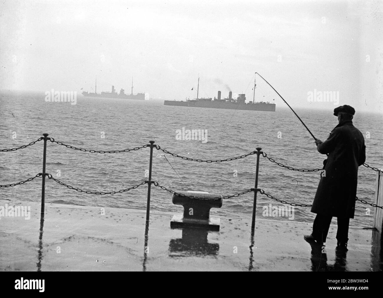 Er hat ein Mystery-Kriegsschiff angespannt. Der belgische Mystery Zerstörer von einem Fischer angespannt . In der Ferne ist die portugiesische Schiffstransport Gil Eanes. Oktober 1935 Stockfoto