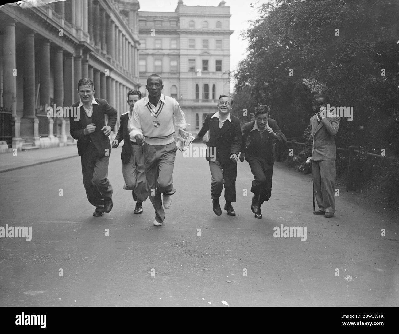 Jesse Owens macht London Street zu seiner Rennstrecke. Jesse Owens, der "Black Panther" und Gewinner von 3 olympischen Goldmedaillen, gab eine Demonstration zu London Jungen, die ihn für die Ressource Transplantat in seinem Hotel nach seiner Ankunft aus Deutschland belagert. Owens ist im britischen Empire, Vereinigten Staaten Leichtathletik in der Weißen Stadt (Samstag) zu konkurrieren. Foto zeigt, Jesse Owens läuft mit Jungen außerhalb des Londoner Hotels. Bis 14. August 1936 Stockfoto