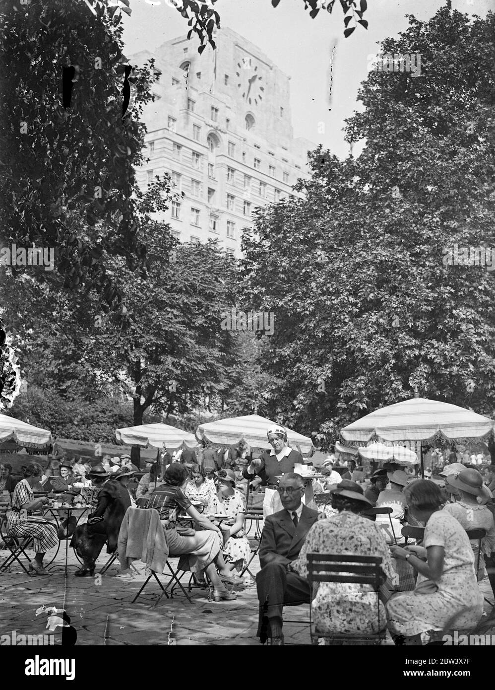 London hat Mittagessen im Freien. Foto zeigt, Mittagessen im Schatten der grünen Bäume in Embankment Garden, während der Mittagshitze. Die Uhr war kein willkommener Begleiter. 24. August 1936 Original-Bildunterschrift von Negativ Stockfoto