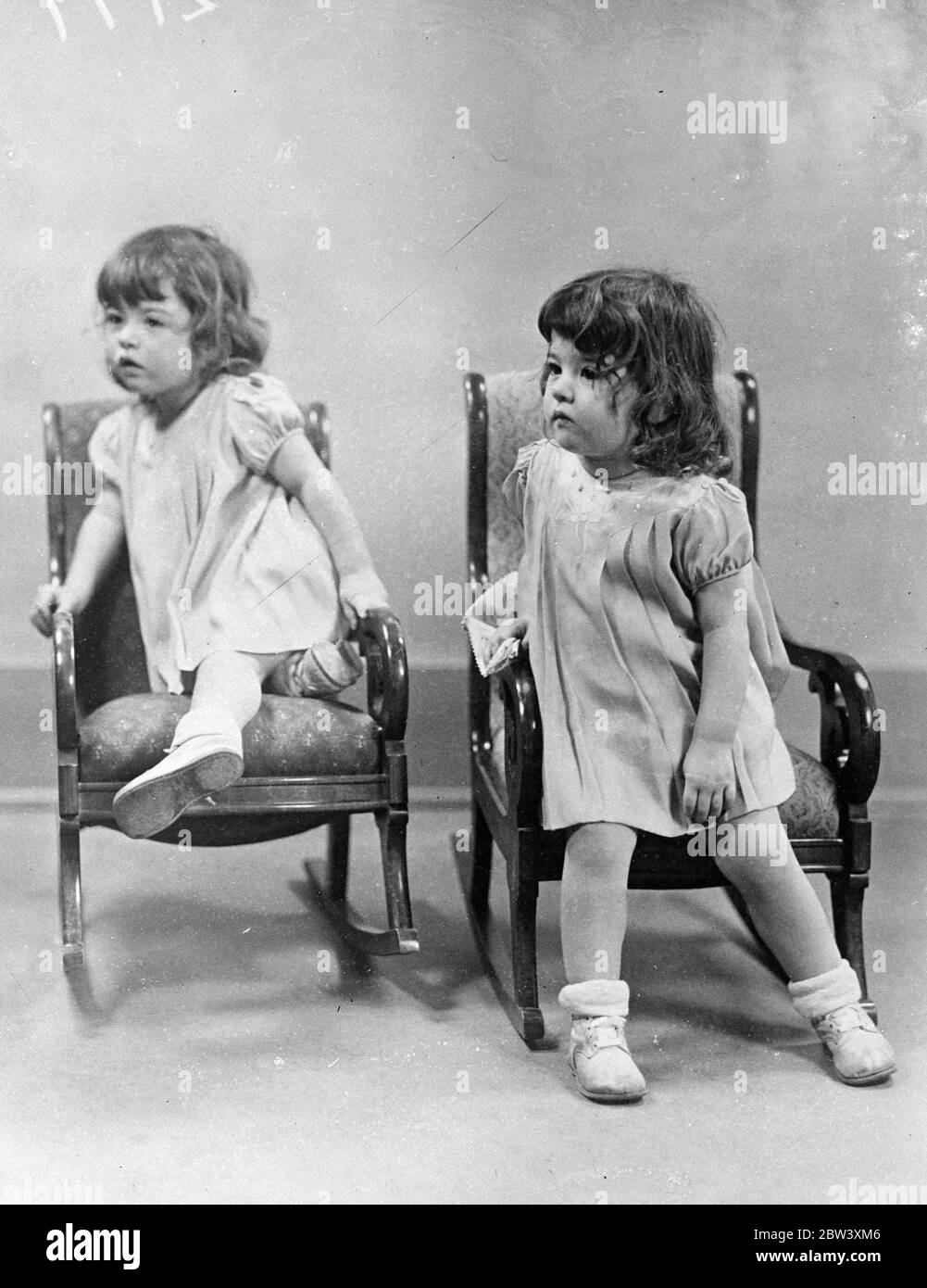 Etwas Interessantes ist in der Dionne-Fünfkärge in Callender, Ontario passiert - so interessant, dass Emily (links) und Yvonne ihre bequemen neuen Schaukelstühle am 28. März 1937 vergessen Stockfoto