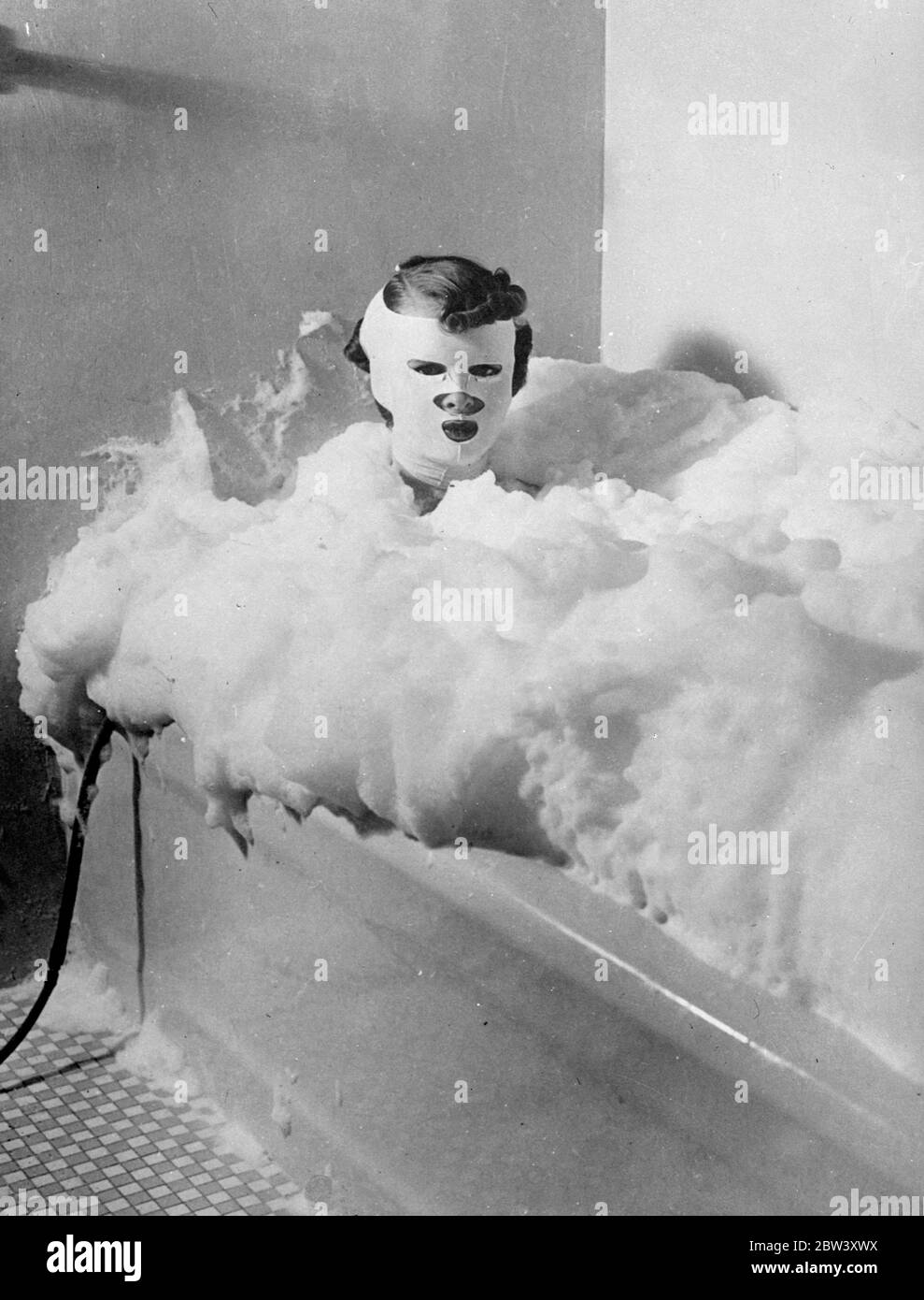 Schönheit durch "Massenproduktion" Methoden. Beauty-Behandlung wurde auf den Linien der "Big Business" in Amerika und "Massenproduktion" Methoden in den Salons eingeführt organisiert. Obwohl der Kunde nicht tatsächlich auf einem beweglichen Gürtel platziert , sie bewegt sich von einer Abteilung zur anderen für jede besondere Behandlung , wie diese Serie von Bildern , in einer Fifth Avenue , New York , Salon , zeigt . Foto zeigt, trägt eine spezielle Maske entwickelt, um Jugendliche Konturen auf das Gesicht wiederherzustellen, nimmt der Kunde ein Milchbad. Druckluft in die Milch gezwungen macht den Schaum. 13 März 1937 Stockfoto