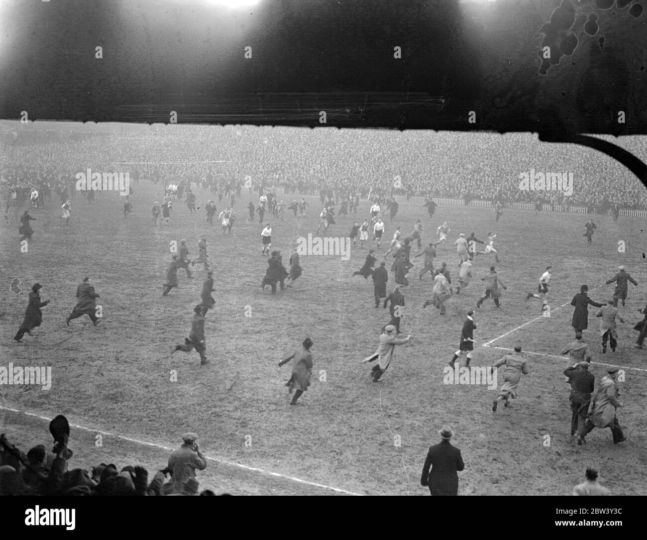 Millwall Spieler fliehen, wie Tausende Feld nach Cup Unentschieden Sieg eindringen. Millwall Spieler mussten vom Spielfeld fliehen, als Tausende ihrer überfreudeten Fans nach dem 2 - 0 Sieg des Teams über Manchester City in der sechsten Runde des F A Cup in "The Den", New Cross auf das Feld aufstiegen. Bald war das ganze Feld mit Tausenden von Menschen eingeklemmt. Foto zeigt, Millwall Spieler werden über den Platz von ihren begeisterten Bewunderern nach dem Spiel gejagt. März 1937 Stockfoto