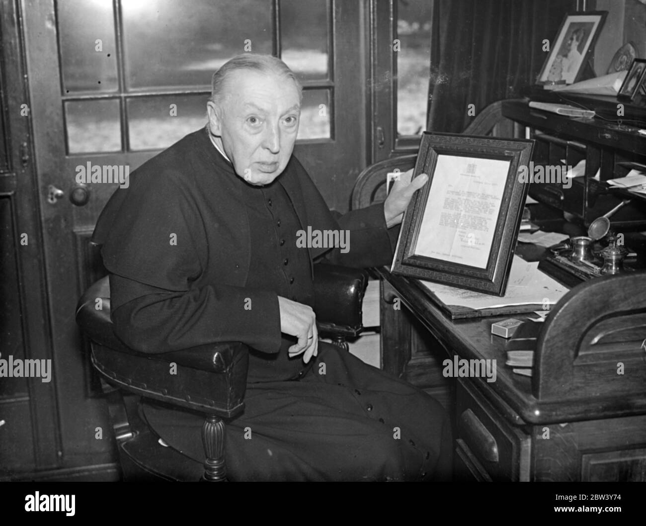 74 Jahre alte Priester Brief verursacht Königin Holyweek Partei verschieben. Ein Brief von 74 Jahre alten anglo-katholischen Priester Pater Herbert Williams von St. Alban ' s Church , teddington , darauf hinweist, dass ein Buckingham Palace Partei in Holyweek statt hat die Königin verursacht, um die Funktion zu verschieben . In ihrer Antwort, die Vater Williams hat gerahmt, die Königin dankte ihm für seinen Brief. Pater Williams feierte im vergangenen Jahr das Jubiläum seines Priestertums. Foto zeigt, Pater Herbert Williams liest die Königin ' s Brief, die er in seinem Teddington Haus gerahmt hat. März 1937 Stockfoto