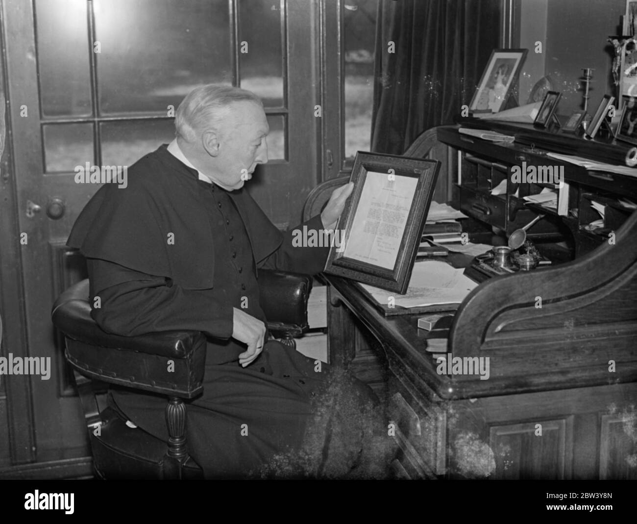 74 Jahre alte Priester Brief verursacht Königin Holyweek Partei verschieben. Ein Brief von 74 Jahre alten anglo-katholischen Priester Pater Herbert Williams von St. Alban ' s Church , teddington , darauf hinweist, dass ein Buckingham Palace Partei in Holyweek statt hat die Königin verursacht, um die Funktion zu verschieben . In ihrer Antwort, die Vater Williams hat gerahmt, die Königin dankte ihm für seinen Brief. Pater Williams feierte im vergangenen Jahr das Jubiläum seines Priestertums. Foto zeigt, Pater Herbert Williams liest die Königin ' s Brief, die er in seinem Teddington Haus gerahmt hat. März 1937 Stockfoto