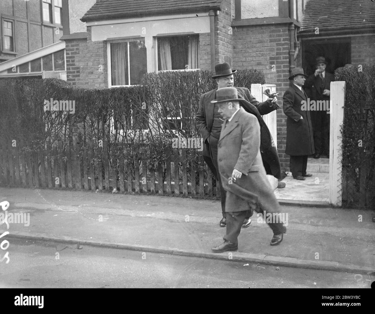 Ehemann einer ermordeten Frau besucht den Tatort. Scott, Ehemann der ermordeten Frau, und Superintendent Sands, Die für die Ermittlungen verantwortlich ist, besuchte das Haus in Idmiston Road, Worcester Park, Surrey, wo Frau Sarah Alice Scott, etwa 50 Jahre alt, von ihrem Sohn Donald tot mit Kopfverletzungen und einem Schal um den Hals gefunden wurde. Foto zeigt: Mr Scott (im Vordergrund) verlässt den Tatort mit Superintendent Sands. März 1937 Stockfoto