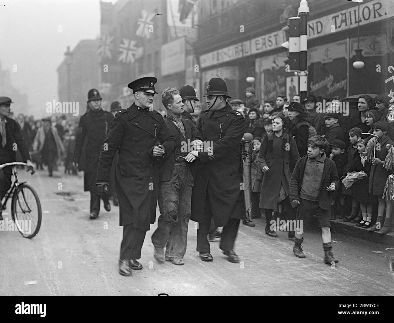 Polizei verhaften Mann als König und Königin angekommen im Volkspalast. Als der König und die Königin am neuen Gebäude ankamen, verhaftete die Polizei einen Mann in der Mile End Road vor dem Volkspalast. Der König und die Königin nahmen an der ersten öffentlichen Verlobung zusammen seit dem Aufstieg Teil. Foto zeigt, marschiert die Polizei weg der verhaftete Mann aus dem Volk ' s Palast. 13 Februar 1937 Stockfoto