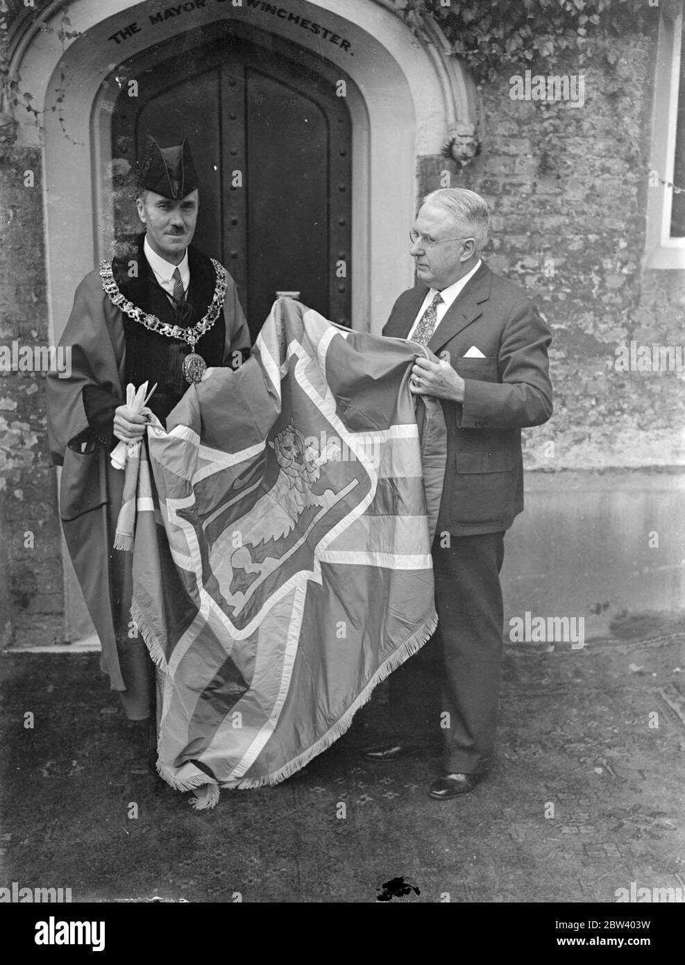Bürgermeister von Winchester (Virginia) überreicht Flagge an Bürgermeister von Winchester (England). DR C. R. Anderson, der Bürgermeister von Winchester, Virginia, USA, überreichte dem Bürgermeister von Winchester, Hampshire, in der Winchester Guildhall die große Seidenfahne, den eingeschriebenen Schlüssel und das Gestrüppe, die das Geschenk des amerikanischen Winchester an die Leute ihrer englischen Namensgeberstadt sind. Die Flagge ist eine Nachbildung der Stadtflagge von Winchester, Virginia. Foto zeigt: Der Bürgermeister von Winchester, Virginia, Dr. C. R. Anderson, übergab die Flagge dem Bürgermeister von Winchester, England, Ratsmitglied A. T. Edmonds (Roben) in Winchester, Hants. 16 S Stockfoto Bürgermeister von Winchester (Virginia) überreicht Flagge an Bürgermeister von Winchester (England). DR C. R. Anderson, der Bürgermeister von Winchester, Virginia, USA, überreichte dem Bürgermeister von Winchester, Hampshire, in der Winchester Guildhall die große Seidenfahne, den eingeschriebenen Schlüssel und das Gestrüppe, die das Geschenk des amerikanischen Winchester an die Leute ihrer englischen Namensgeberstadt sind. Die Flagge ist eine Nachbildung der Stadtflagge von Winchester, Virginia. Foto zeigt: Der Bürgermeister von Winchester, Virginia, Dr. C. R. Anderson, übergab die Flagge dem Bürgermeister von Winchester, England, Ratsmitglied A. T. Edmonds (Roben) in Winchester, Hants. 16 S Stockfoto