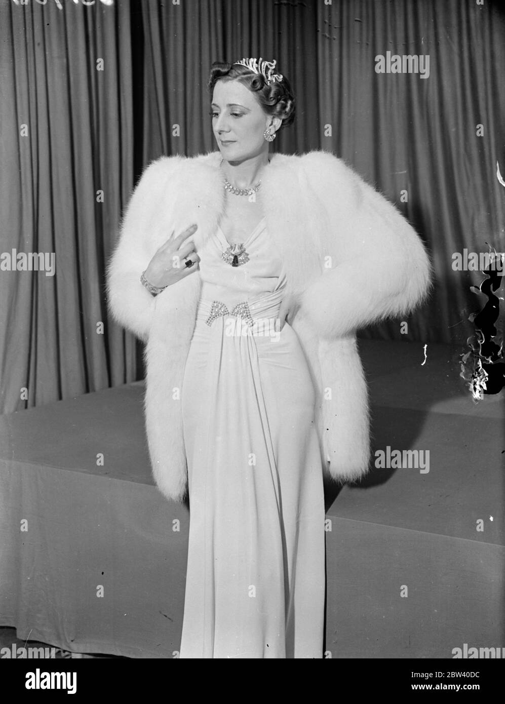 Court Kleid mit £20,000 Schmuck auf der London Exhibition gezeigt. Wunderschöne Kleider, die während der Krönungssaison zu sehen sein werden, wurden auf der Krönungsausstellung von britischen Kleidern Designer gezeigt, die Prinzessin Beatrice im Großen Raum im Grosvenor Haus, Park Lane eröffnete. Die Ausstellung wird im Rahmen des Sunshine Home for Blind Babies veranstaltet. Foto zeigt: Theresa - ein Court Ball Kleid von Isabel. Mit diesem Kleid der Mannequin trägt Juwelen im Wert von £20,000 und einem weißen Fuchspelz bei 100 guineas bewertet. April 1937 Stockfoto