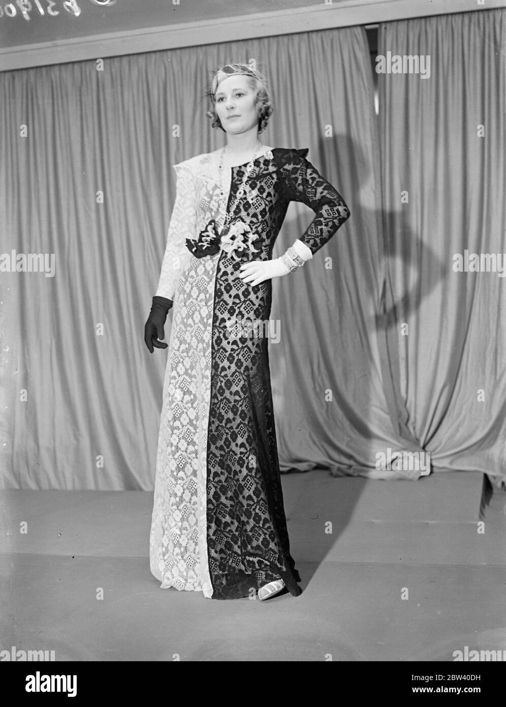 Krönungskleider auf der Londoner Ausstellung. Wunderschöne Kleider, die während der Krönungssaison zu sehen sein werden, wurden auf der Krönungsausstellung von britischen Kleidern Designer gezeigt, die Prinzessin Beatrice im Großen Raum im Grosvenor Haus, Park Lane eröffnete. Die Ausstellung wird im Rahmen des Sunshine Home for Blind Babies veranstaltet. Foto zeigt: Ein schwarz-weißes Diner-Kleid aus feiner Wollspitze - Whisky - von Ulick Philippe 7. April 1937 Stockfoto