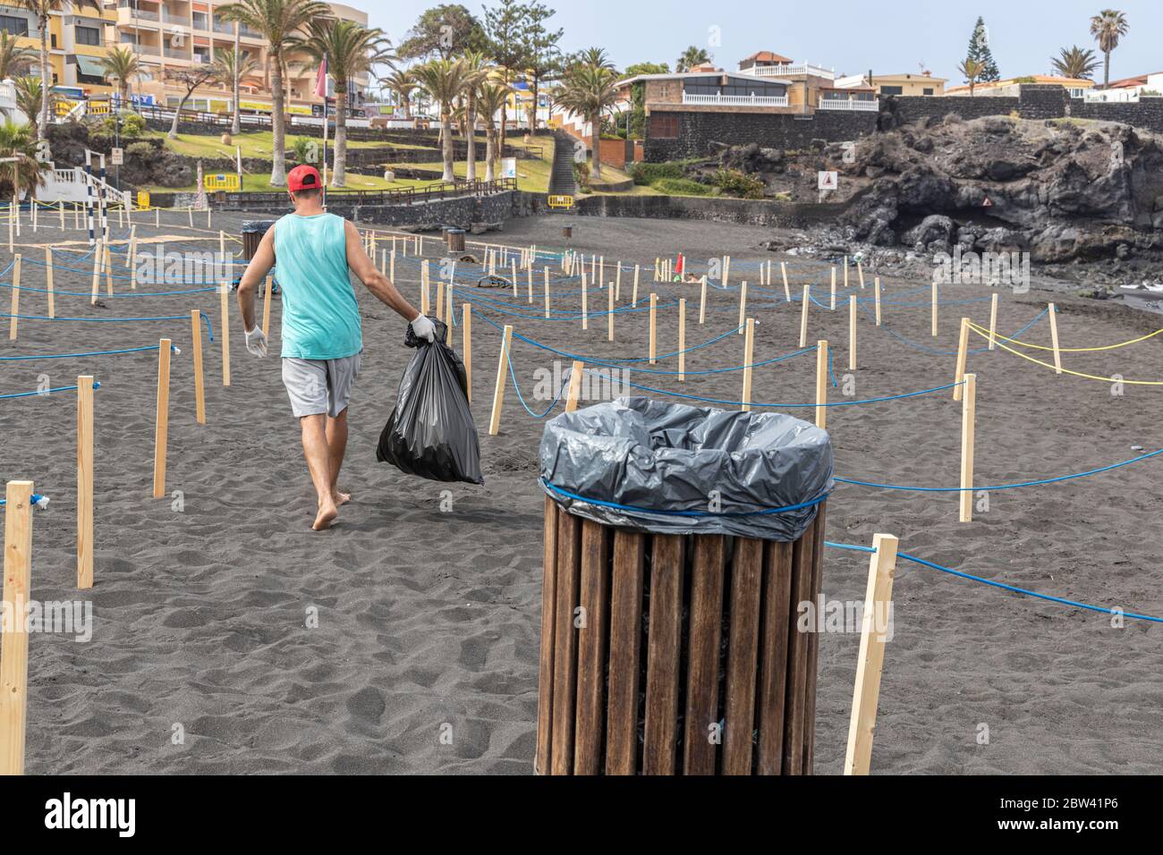 Arbeiter leert Mülltonne am Strand mit abgesperrten Bereichen, um die soziale Distanz, zwei Meter voneinander entfernt, und kontrollierten Zugang für die Öffentlichkeit zu erhalten Stockfoto