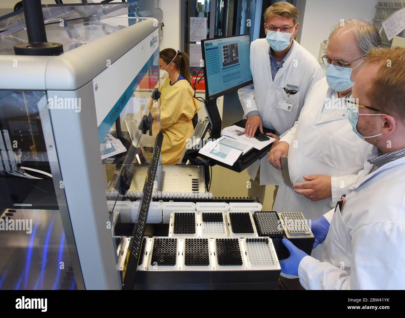 29. Mai 2020, Sachsen, Leipzig: Am Institut für Molekularbiologie für Virologie am Universitätsklinikum Leipzig, Infektologe Prof. Christoph Lübbert (l.), Leiter der Abteilung für Infektions- und Tropenmedizin, Und der Institutsleiter, der Virologe Prof. Uwe G. Liebert, informiert mit einem diagnostischen Gerät gemeinsam mit dem Biologen Tom Berthold über den Verlauf der groß angelegten Corona-Studie zum Auftreten von Infektionen bei Schülern und Lehrern. Seit einigen Tagen werden an verschiedenen sächsischen Schulen freiwillige Rachenabstriche und Serumproben von Schülern und Lehrern entnommen Stockfoto