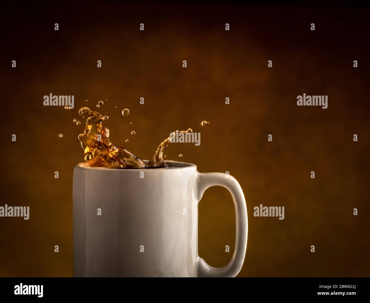 Kaffee spritzt aus Kaffeebecher Stockfoto