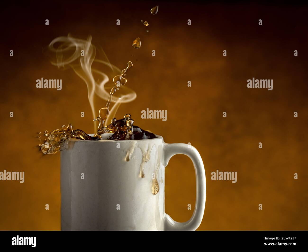 Dampf steigt aus einer Tasse Kaffee, während Kaffee aus der Kaffeetasse spritzt Stockfoto
