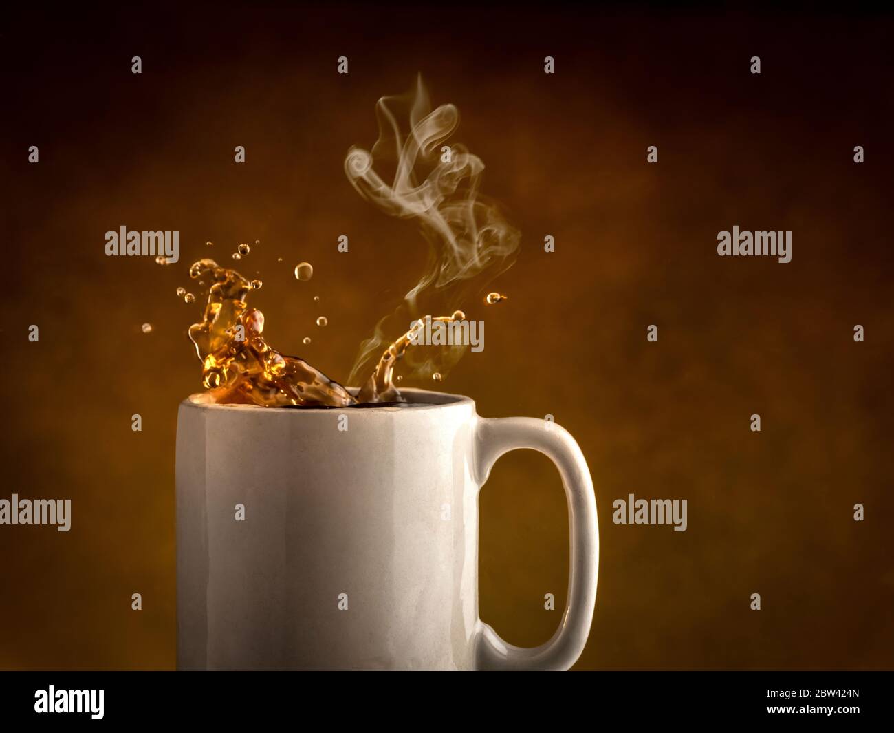 Dampf steigt aus einer Tasse Kaffee, während Kaffee aus der Kaffeetasse spritzt Stockfoto