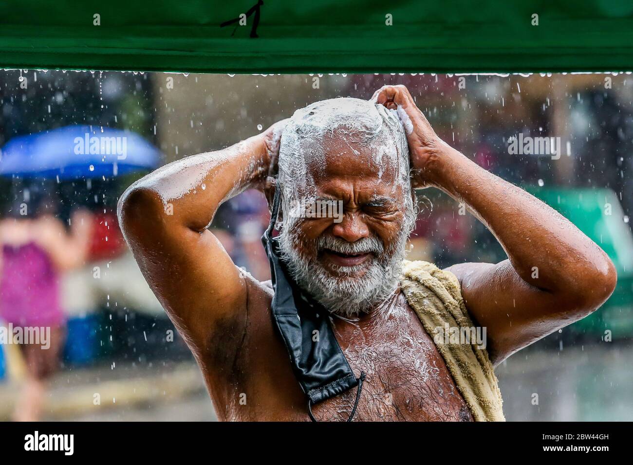 Manila, Philippinen. Mai 2020. Ein Mann nutzt den plötzlichen Regenguss, um in Manila, Philippinen, am 29. Mai 2020, ein Bad zu nehmen. Quelle: Rouelle Umali/Xinhua/Alamy Live News Stockfoto