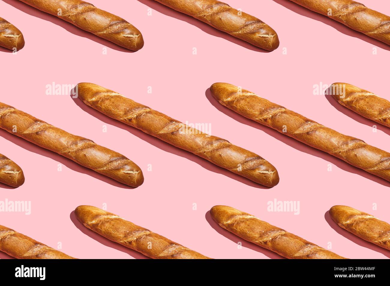 Frisches Brot Baguette Laib auf dem rosa Tisch. Regular Muster, flaches Lay, Draufsicht. Stockfoto