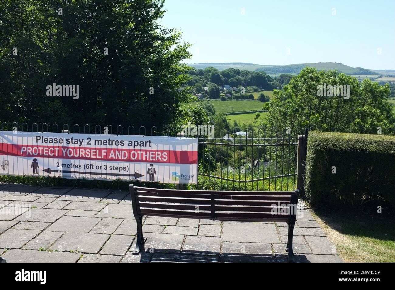Coronavirus Banner erinnert Menschen, getrennt in Shaftesbury Dorset - eine kleine ländliche Marktstadt mit Blick auf die Landschaft. Mai 2020. Stockfoto