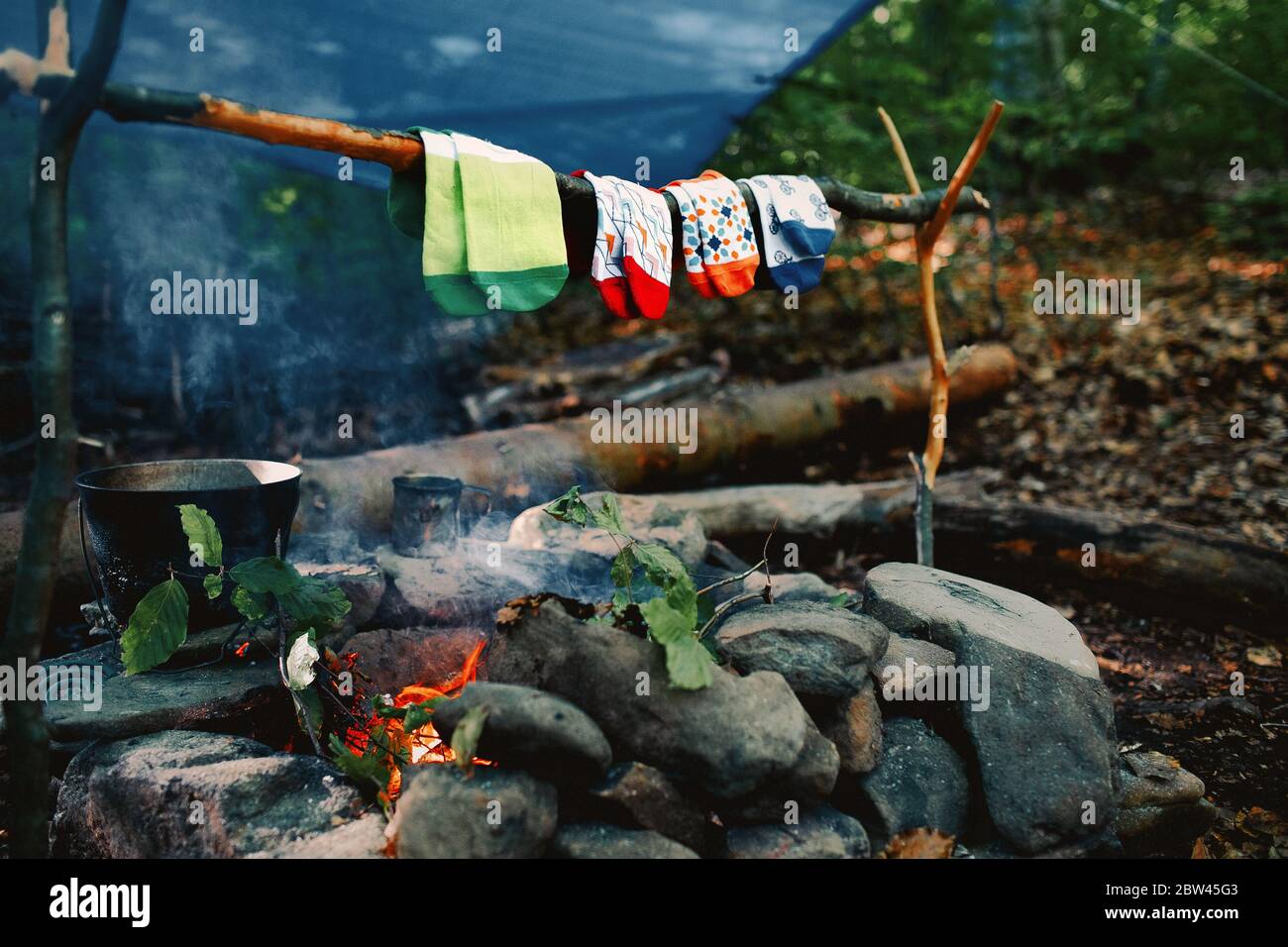 Trocknen nasser Socken am Lagerfeuer während des Campens. Socken trocknen auf Feuer. Aktive Erholung im Wald. Stockfoto