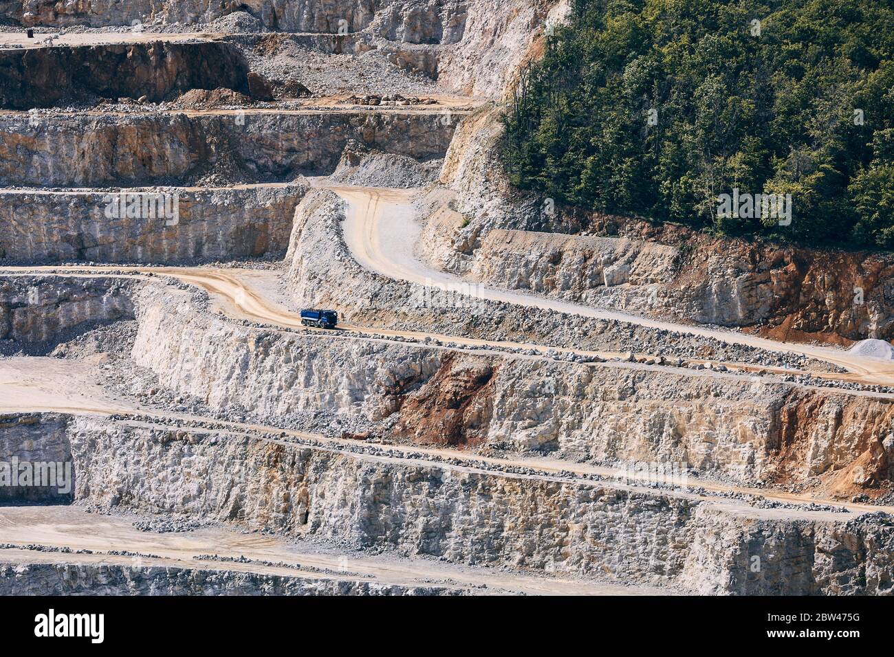 Industrieller Steinbergbau. LKW in der Mitte des riesigen Steinbruchs. Stockfoto