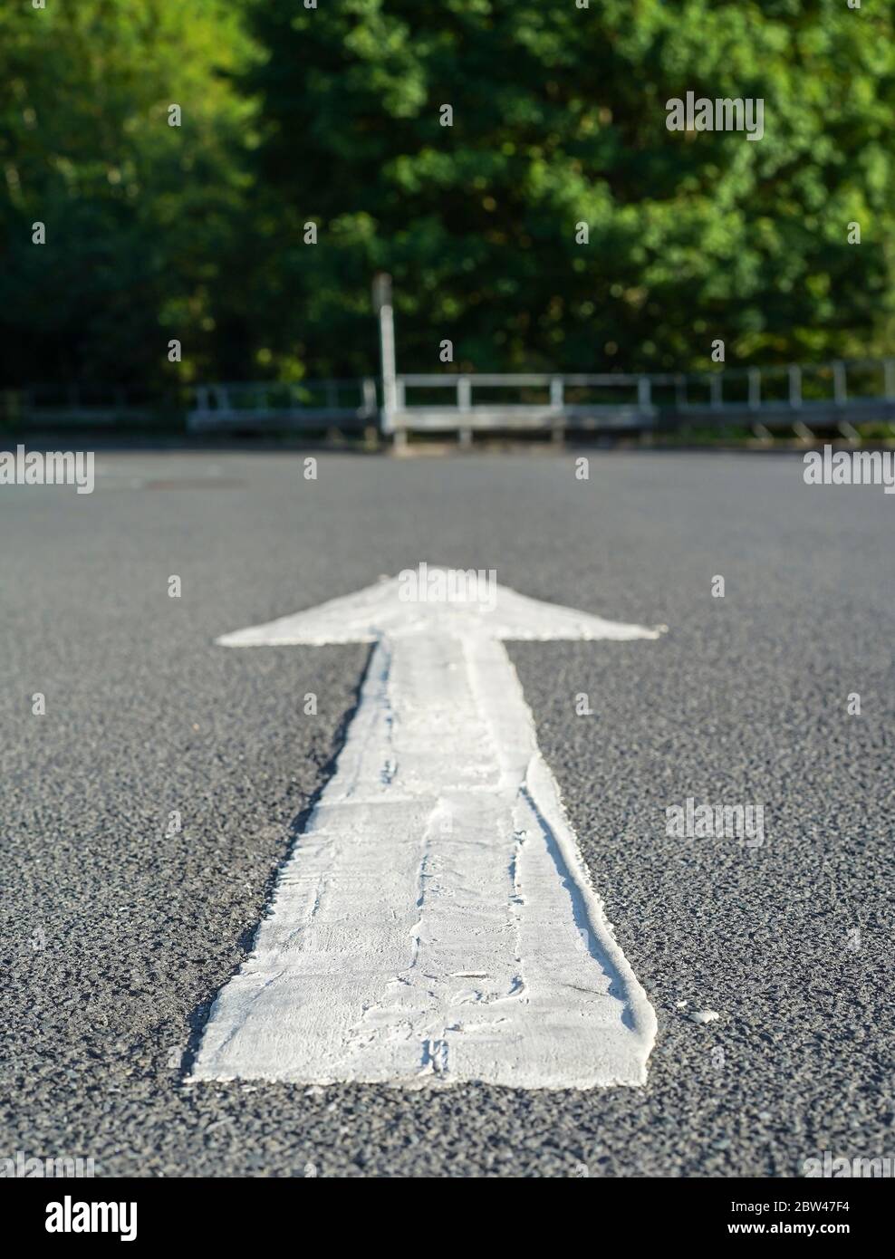 Nahaufnahme von bemalten weißen Pfeil auf dem Boden Asphalt in UK Supermarkt Outdoor Parkplatz, Sommer Sonnenschein. Stockfoto