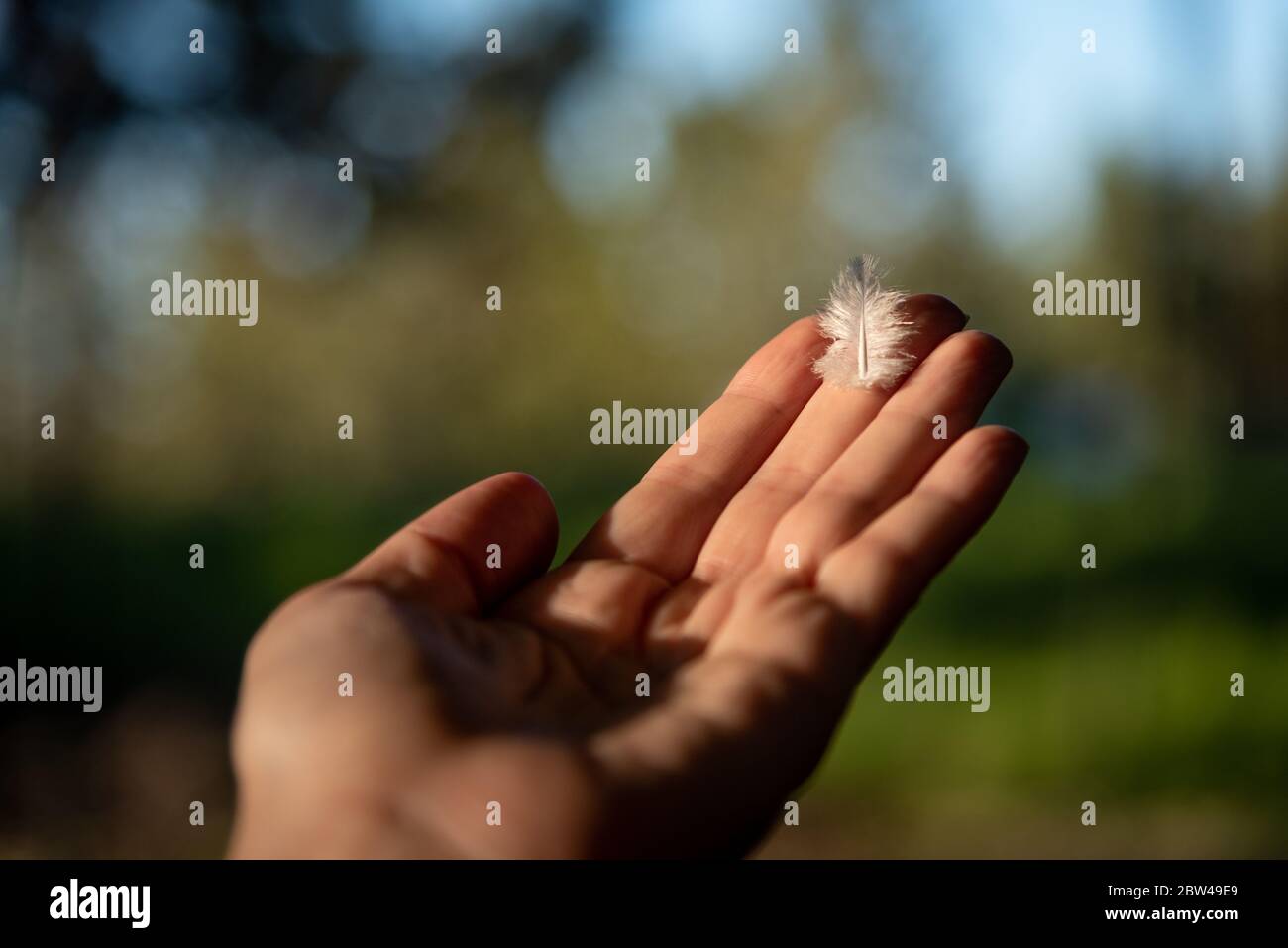 kaukasische Frau, die eine Feder am blauen Himmel hält Stockfoto