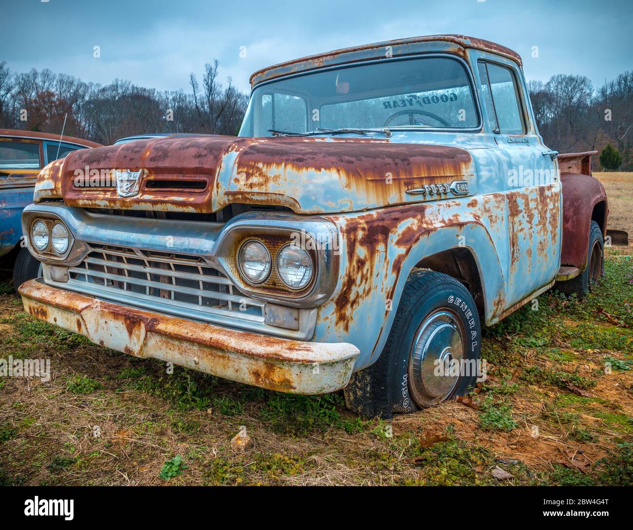 Ein Ford F100 antiker Pickup-Truck parkte auf einem Farmfeld am Straßenrand blau mit rostiger Patina noch in gutem Zustand Stockfoto