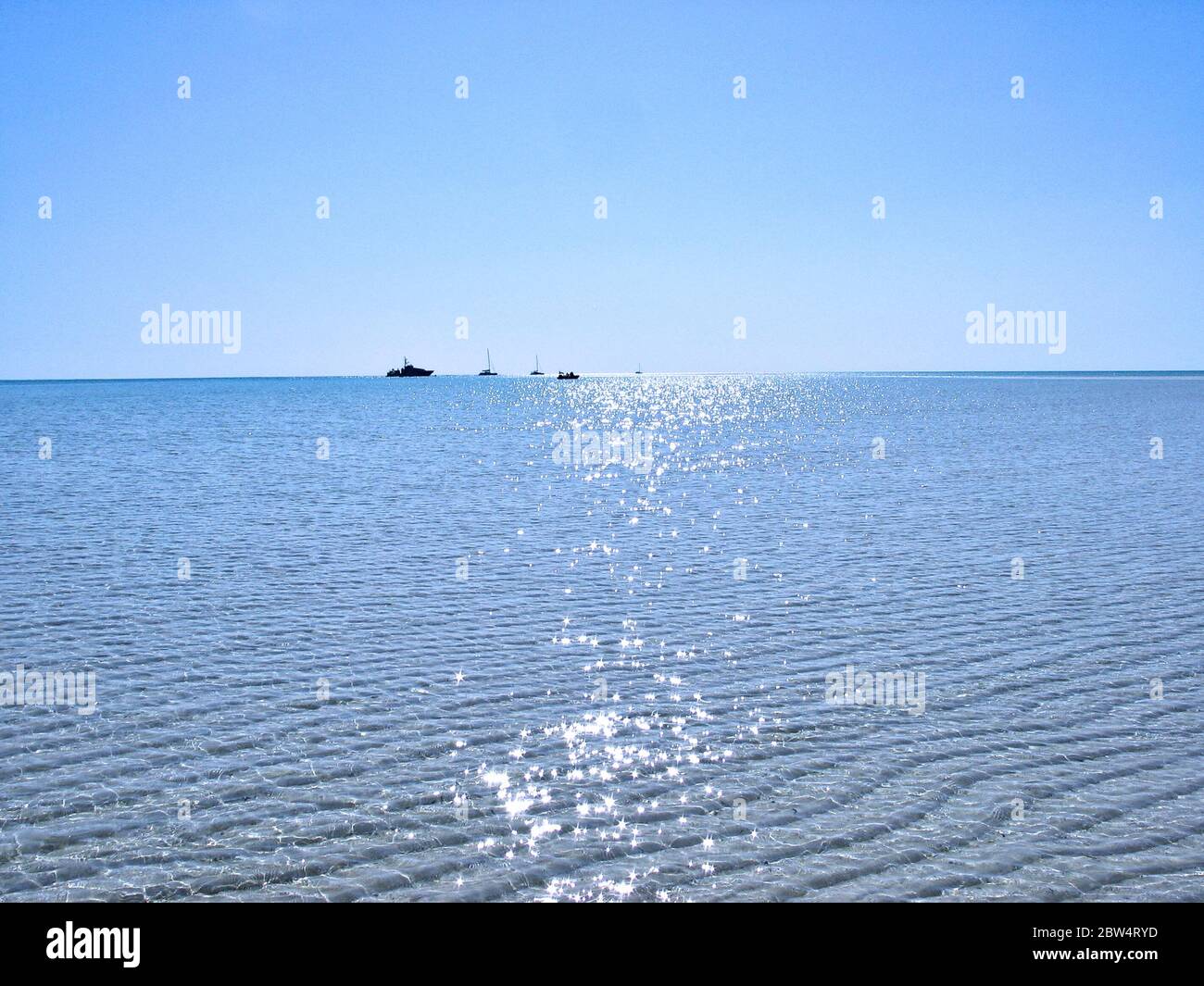 Boote in einem abgelegenen Korallenatoll des Indischen Ozeans verankert, extrem raues direktes Sonnenlicht, Mittag. Stockfoto