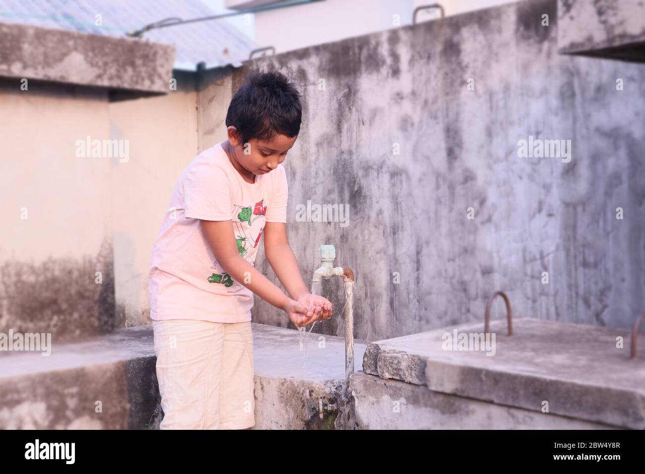 Asiatische Kind Trinkwasser aus dem Wasserhahn im Freien. Konzept für Wassersparen/Knappheit. Stockfoto