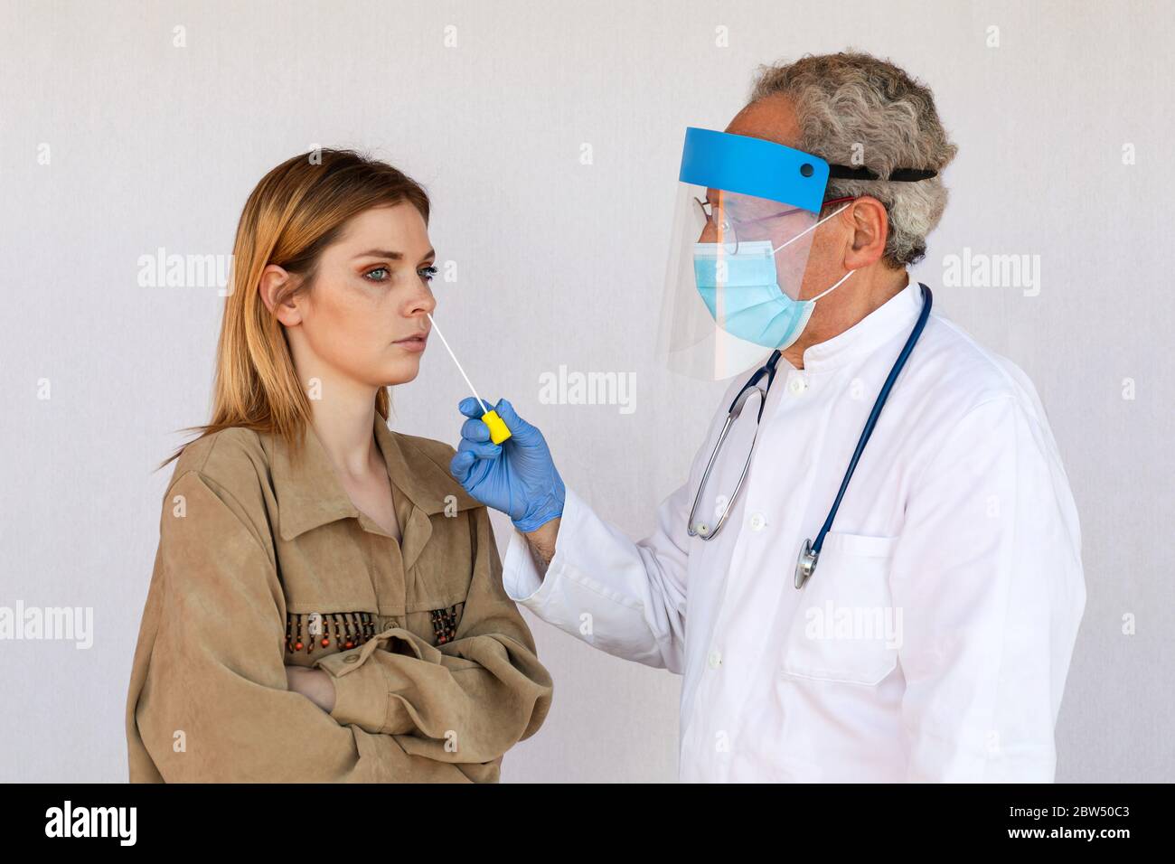 Der Arzt nimmt eine Probe aus dem Nasenloch einer jungen Frau, um anschließend Laboranalysen auf der Suche nach dem SARS-CoV-2-Virus, der Ursache der Ausbreitung, durchzuführen Stockfoto