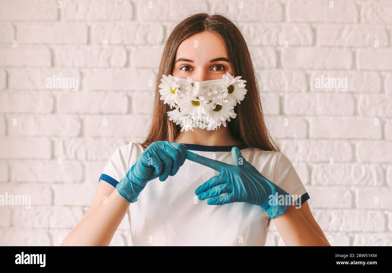 Portrait junges Mädchen Arzt in medizinischen Gesichtsmaske mit Blumen  entfernen Schutzhandschuhe von den Händen. Glücklich schöne Frau in  Schutzmaske feiern e Stockfotografie - Alamy