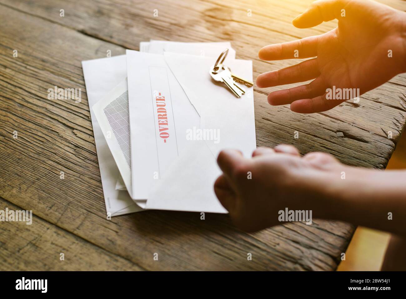 Ausdrucksstarke Hände reagieren auf einen überfälligen Brief im Umschlag - finanzielle Not - Krise Stockfoto