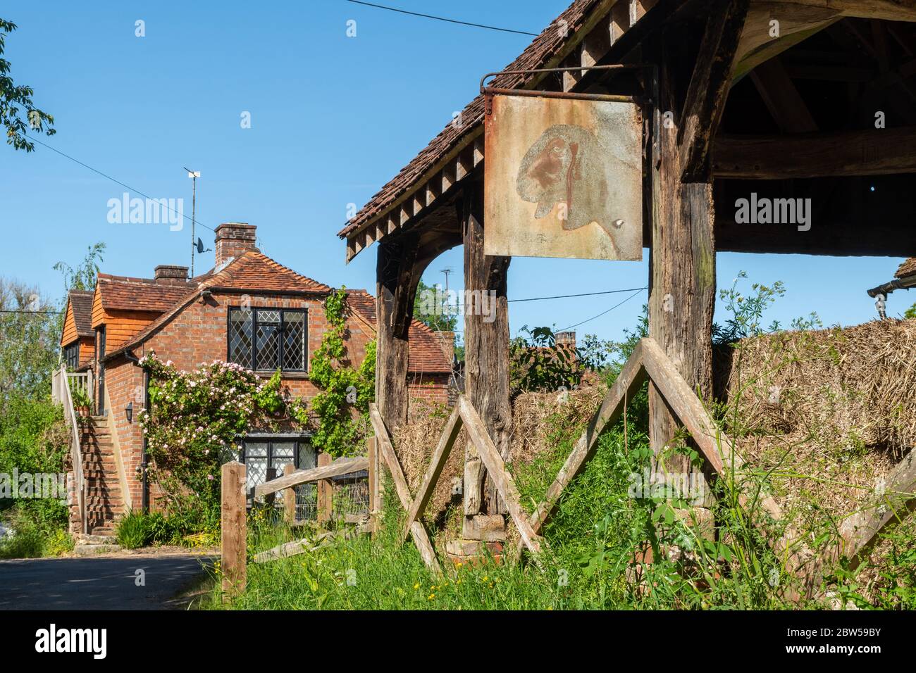 Alte Holzscheune mit offener Seite und umgebautes Bauerngebäude im hübschen ländlichen Weiler Brewhurst bei Loxwood, West Sussex, Großbritannien Stockfoto