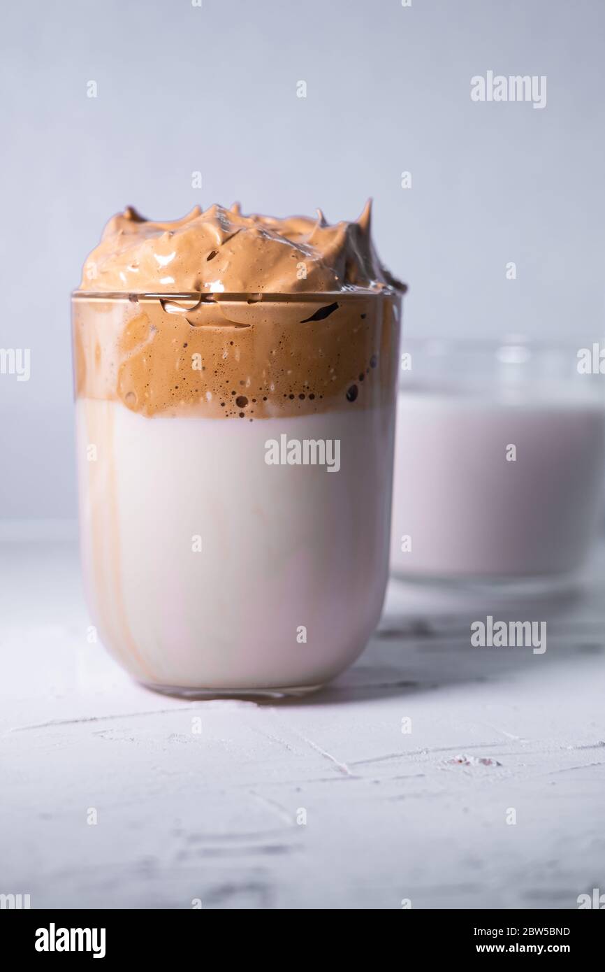 Dalgona Kaffee und Milch im Hintergrund. Koreanischer Eiskaffee. Vertikales Bild. Stockfoto