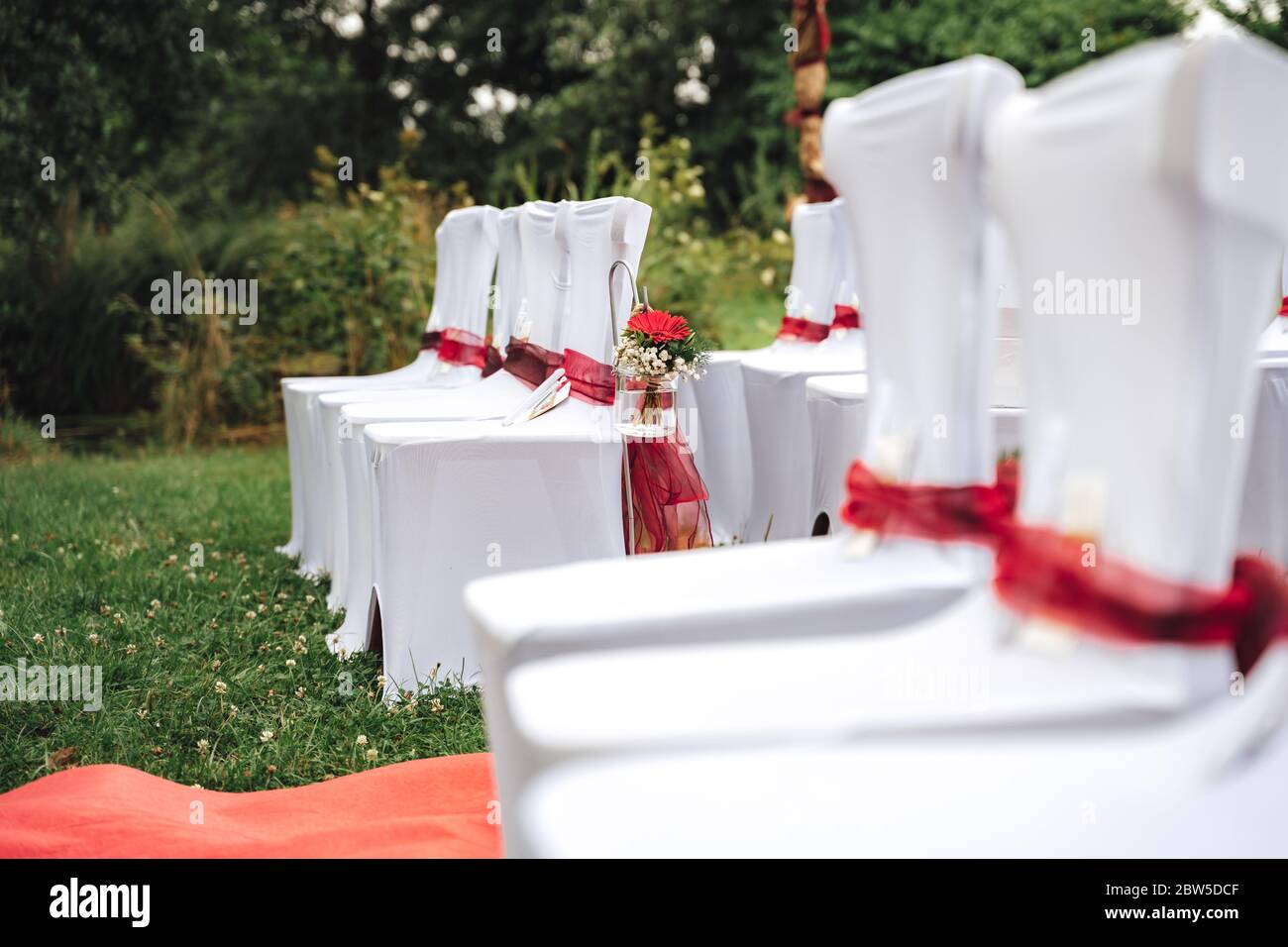 Hochzeitsdekoration: Weiße Stühle auf dem Rasen im Park. Outdoor-NUPTials. Konzept für Hochzeitstag. Stockfoto