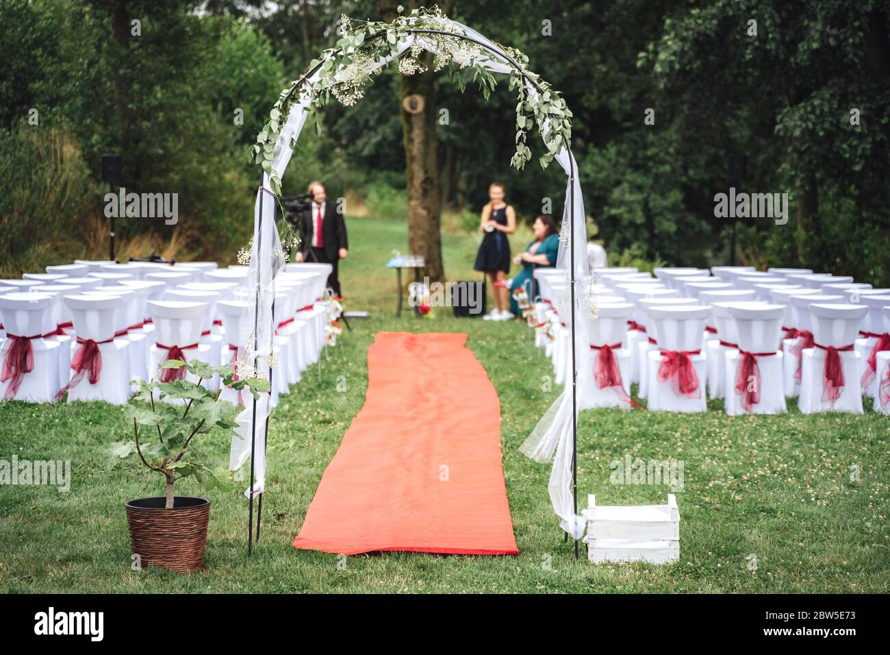 Hochzeitsdekoration - Bogen, Teppich und Stühle auf Rasen im Park. Outdoor-NUPTials. Konzept für Hochzeitstag. Stockfoto