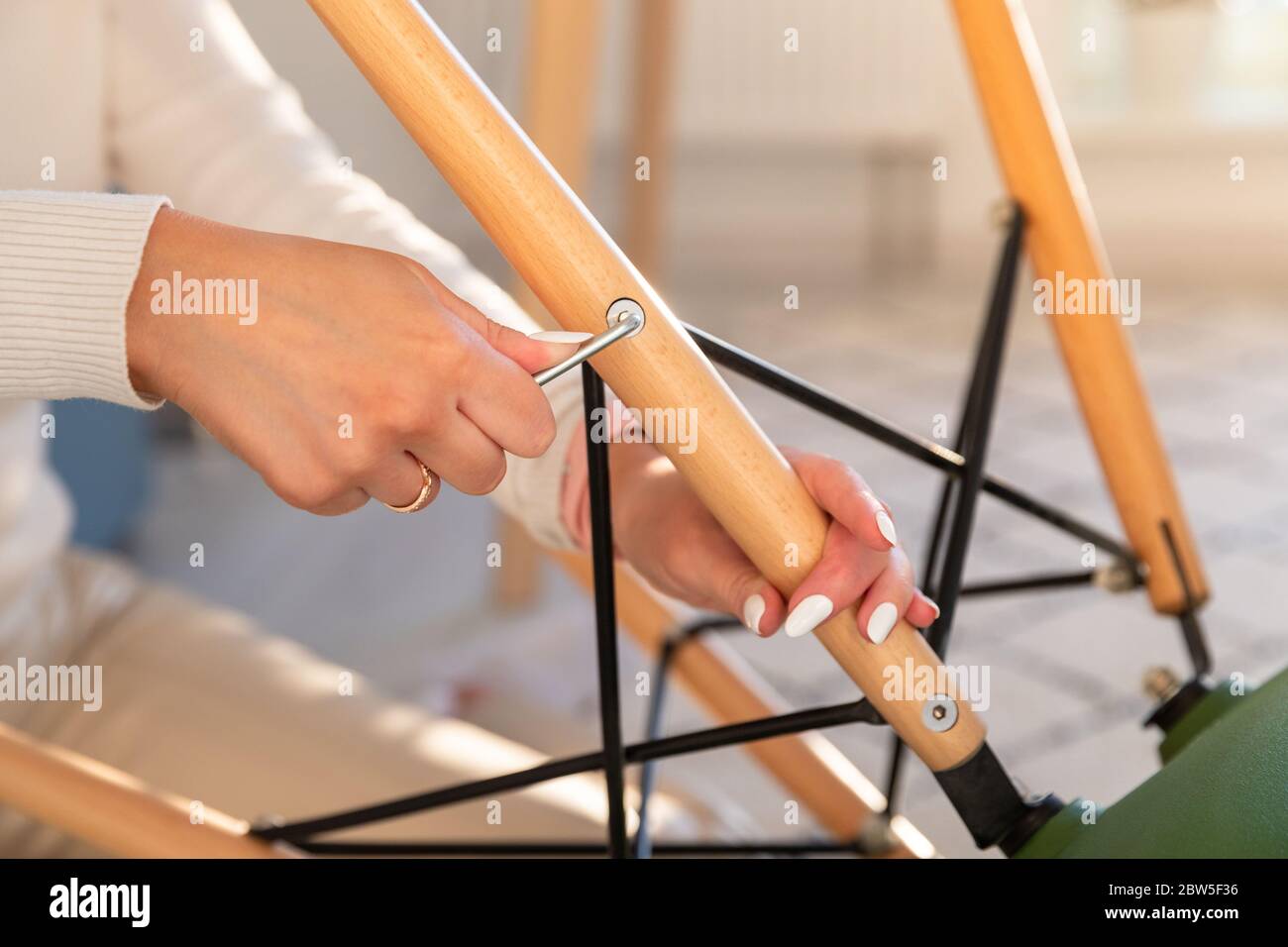 Frau selbst Montage ein Sessel, Festziehen lose Schrauben mit einem Möbel-Innensechskantschlüssel, Nahaufnahme. Stockfoto