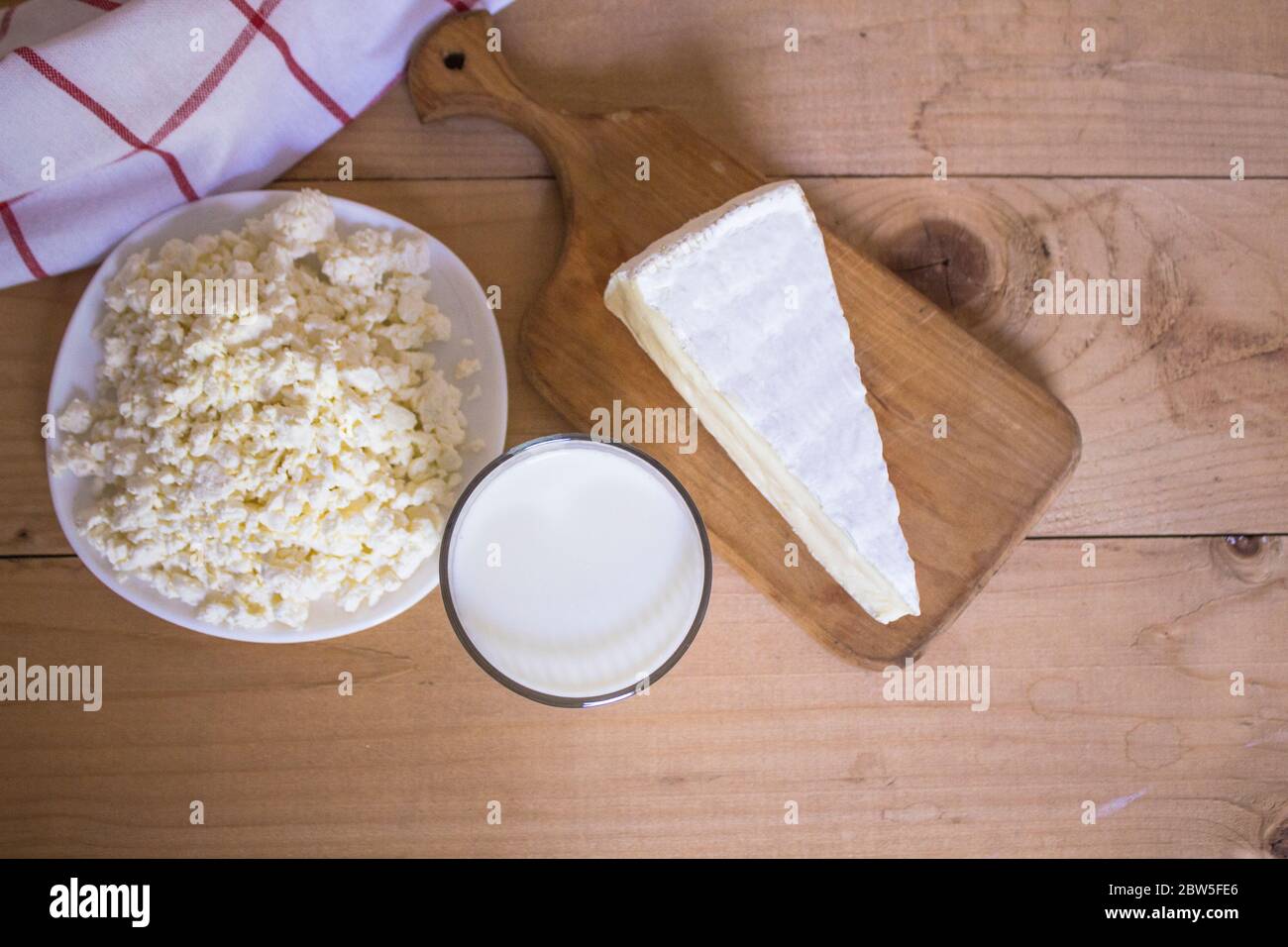 Leckere frische Milch auf einem weißen Holzhintergrund. Glas Milch, Käse auf dem Brett und Hüttenkäse. Blick von oben. Kopierraum Stockfoto