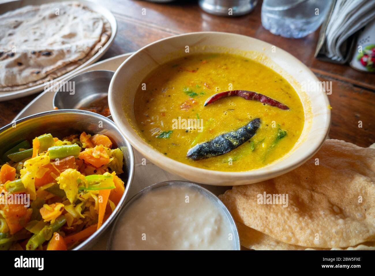 Ein gelbes Curry mit Popadoms, Gemüsesalat und Chapati in einem Restaurant in Mahabalipuram, Indien Stockfoto