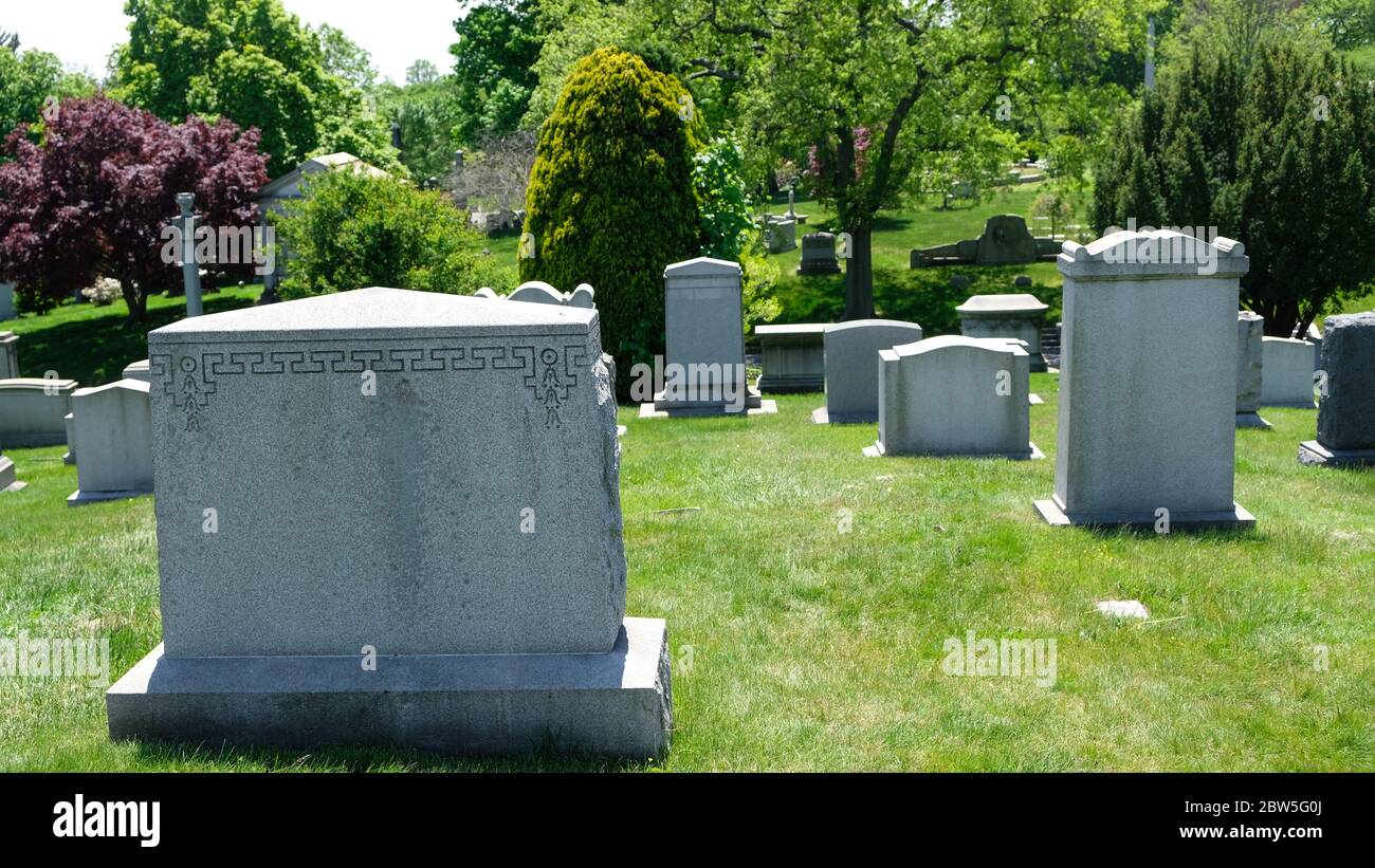 Gräber auf einem schönen Friedhof im Frühling umgeben von grünen Gras und Bäumen Stockfoto