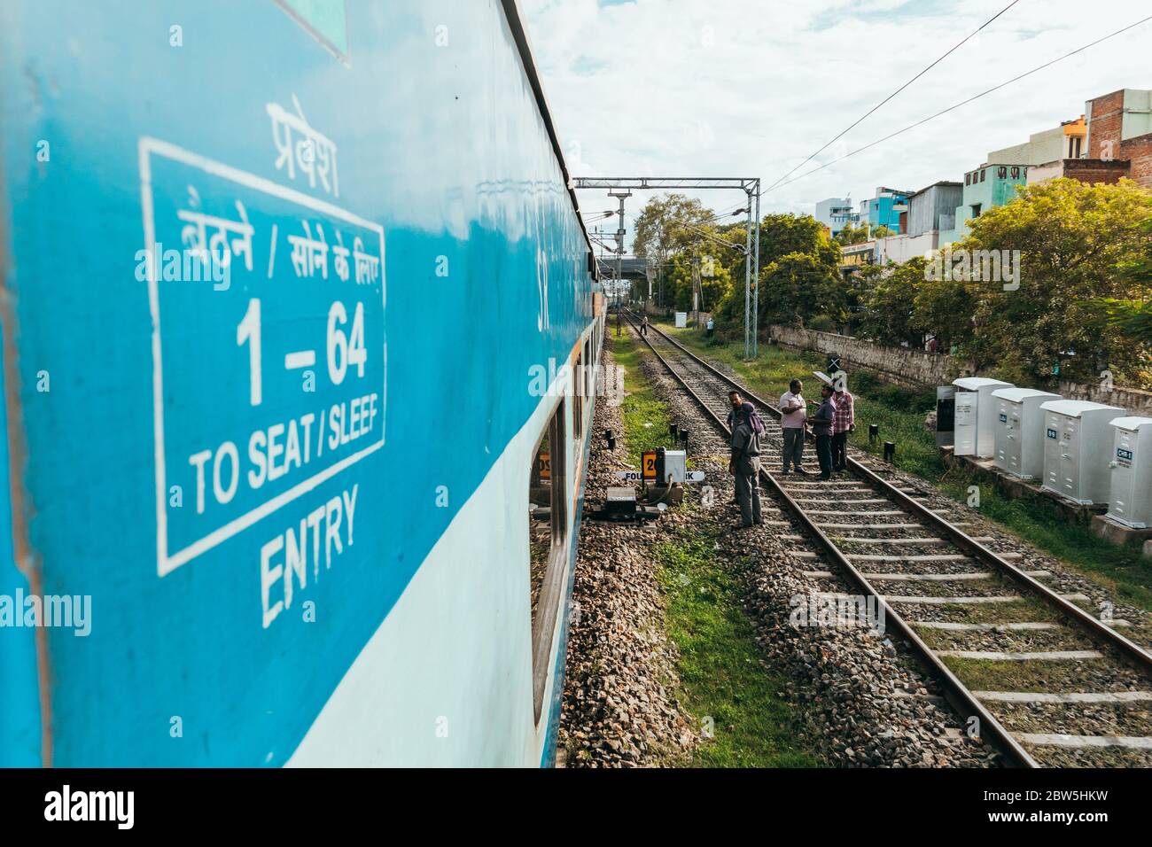 Ingenieure arbeiten auf Eisenbahngleisen, während ein Zug auf einem angrenzenden Gleis außerhalb Madurai, Tamil Nadu, Indien, vorbeifährt Stockfoto