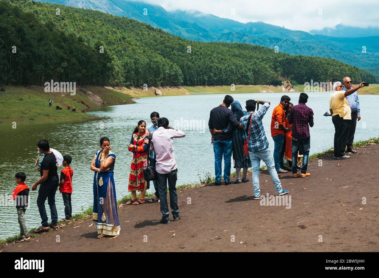 Indische Touristen posieren für Fotos am See am Echo Point, auf dem Mattupatti-Staudamm in Munnar, Kerala, Indien Stockfoto