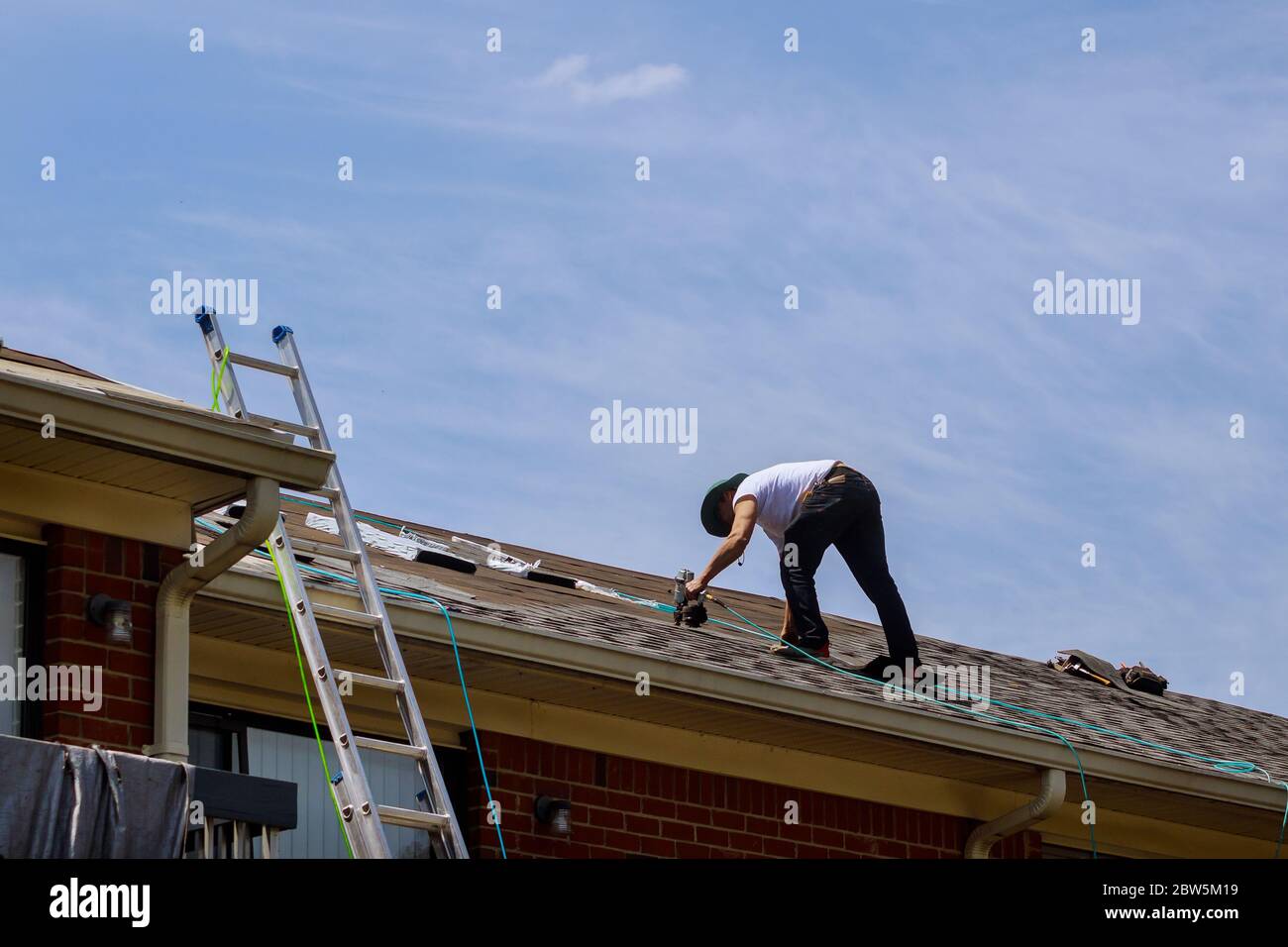 Bauarbeiter Dachdecker auf Dachkonstruktion Anwendung Asphalt Schindeln auf Dach Stockfoto