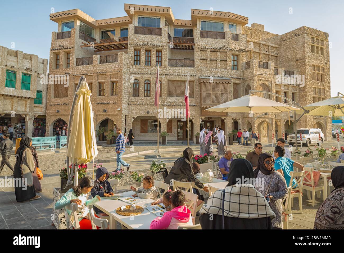 Katarische Frauen und Männer in Souk Waqif, Doha Katar zu Fuß in der Straße und sitzen in einem Restaurant bei Tageslicht Stockfoto