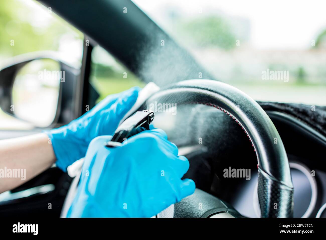 Hände mit blauen Handschuhen, dann Desinfektionsmittel und Reinigung des Autos Stockfoto
