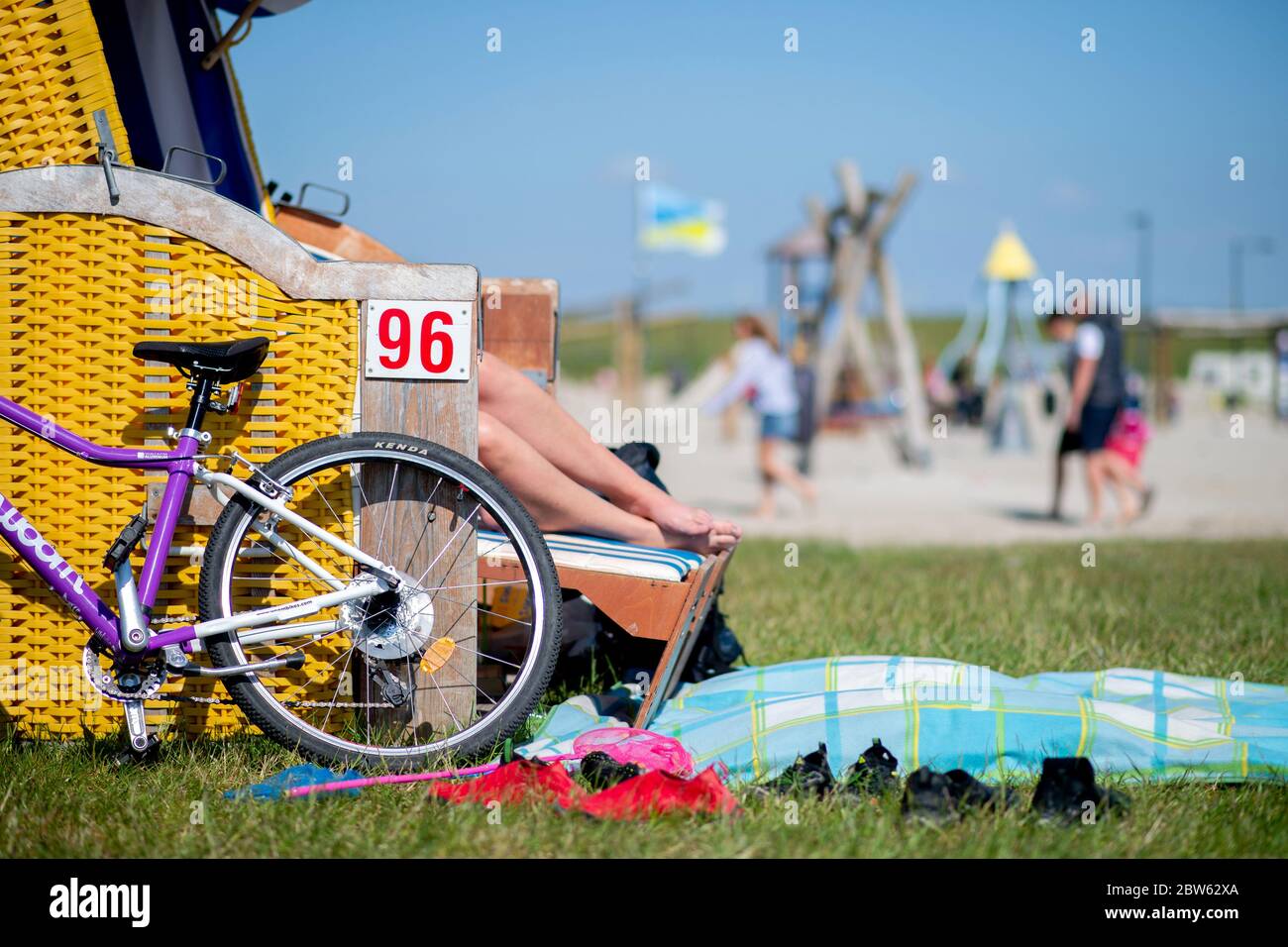 Tossens, Deutschland. Mai 2020. Ein Fahrrad lehnt sich an einen blauen  Liegestuhl an einem gelben Liegestuhl am Friesenstrand im Landkreis  Wesermarsch. Zu Pfingsten werden zahlreiche Urlauber an der  niedersächsischen Küste, auf den